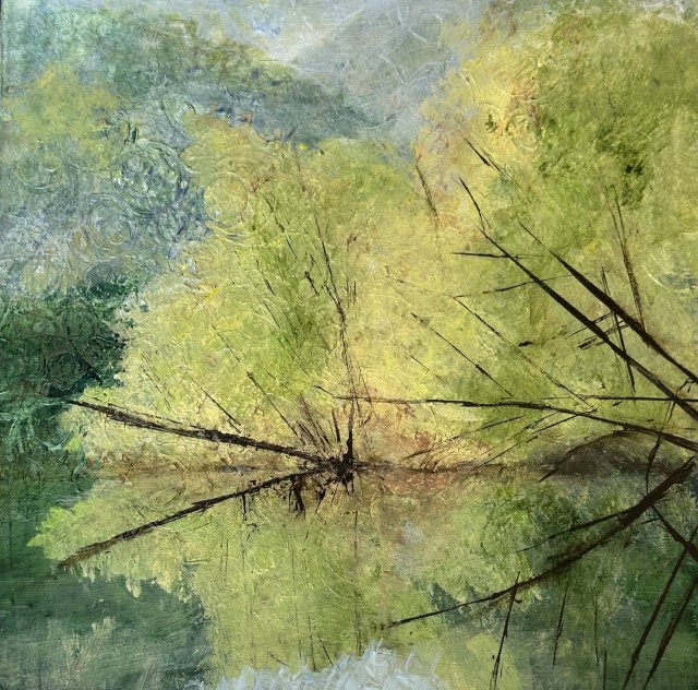 An acrylic painting of a landscape of early autumn trees with tall mountains behind them. The leaves, mostly yellow with some still yellow-green are reflected in a lake in front of them. By Juanita Bellavance